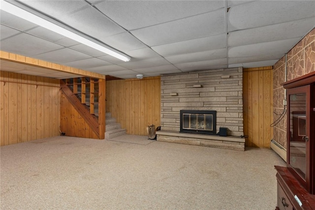 300 Olive St, Watson, IL 62473 - unfurnished living room with a stone fireplace, carpet floors, stairway, wood walls, and a drop ceiling