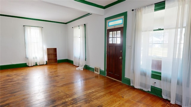 entrance foyer featuring wood-type flooring, crown molding, and a healthy amount of sunlight