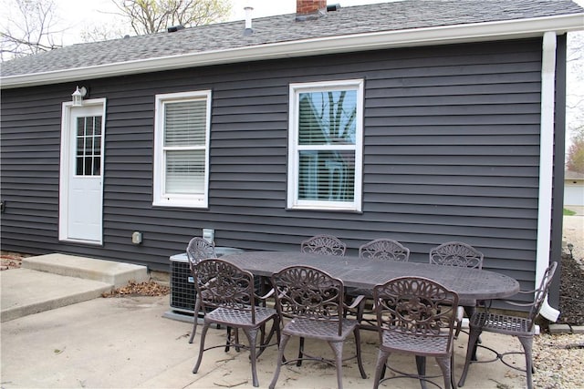 back of property featuring a patio area, central AC unit, a chimney, and a shingled roof