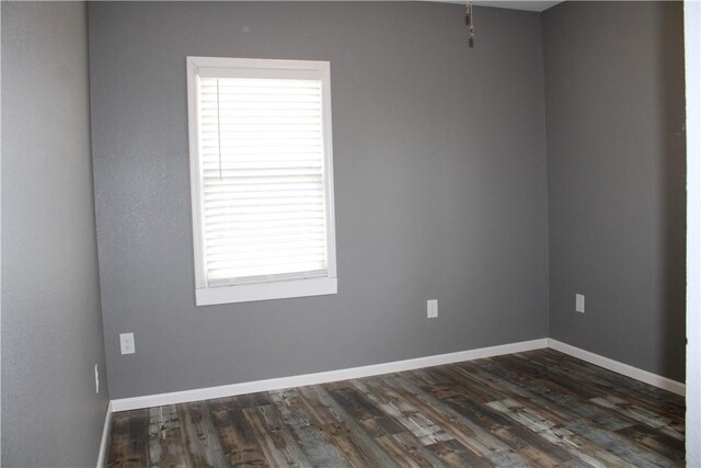 spare room featuring dark wood-type flooring and baseboards