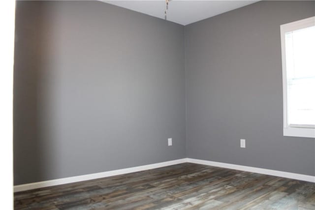 empty room featuring baseboards and dark wood finished floors