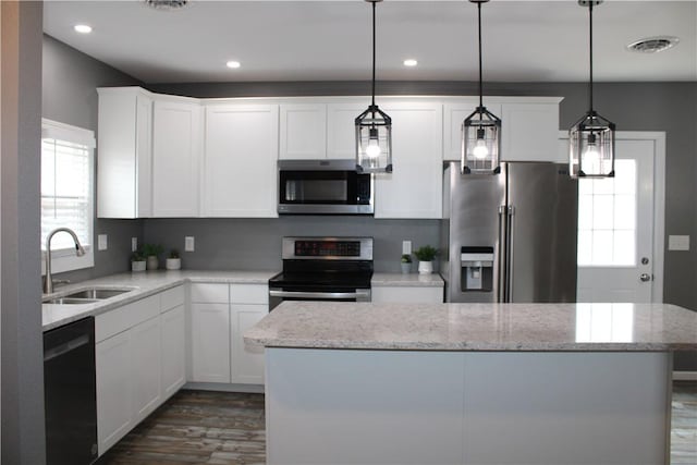kitchen featuring visible vents, a center island, appliances with stainless steel finishes, a sink, and dark wood-style floors