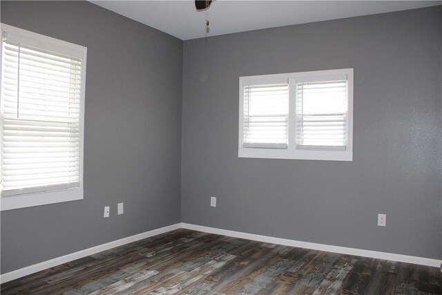 unfurnished room with dark wood-type flooring, a wealth of natural light, ceiling fan, and baseboards