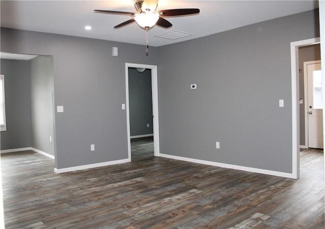 unfurnished room featuring dark wood-type flooring, ceiling fan, baseboards, and visible vents
