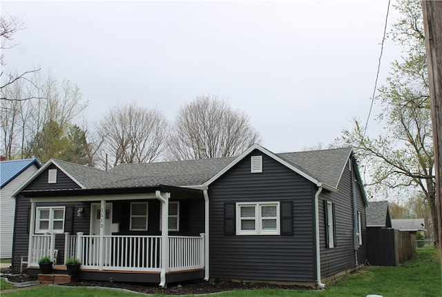 ranch-style home featuring a front yard, a shingled roof, and covered porch