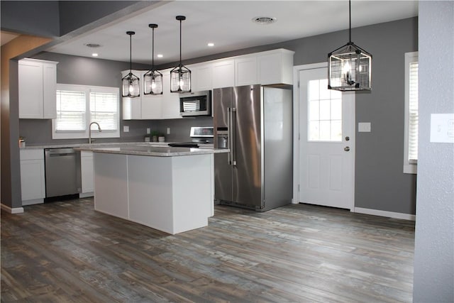 kitchen with visible vents, white cabinets, a center island, dark wood-style flooring, and stainless steel appliances