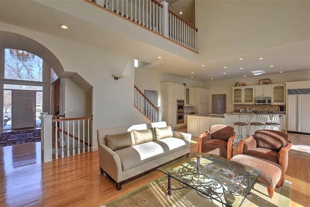 living area with recessed lighting, a high ceiling, and light wood finished floors