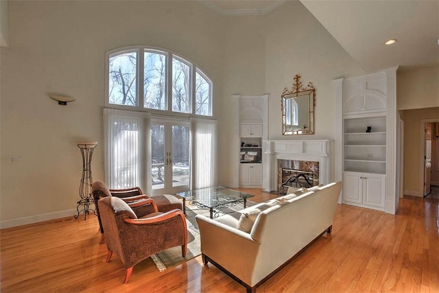 living area with light wood-style flooring, french doors, baseboards, and a premium fireplace