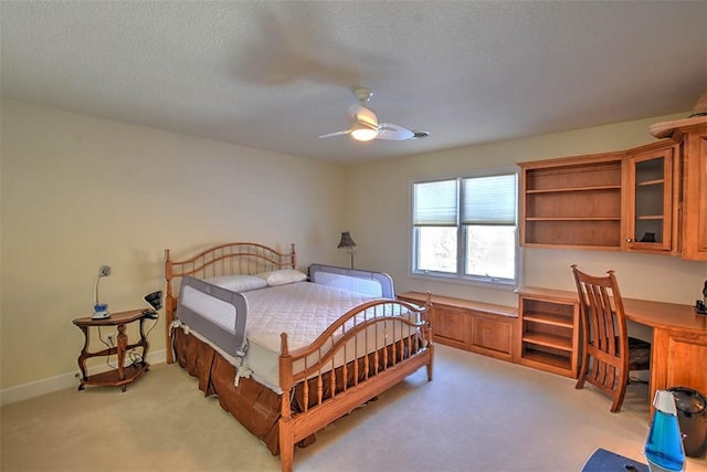 bedroom featuring baseboards, light carpet, a textured ceiling, and built in study area