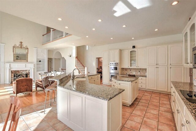 kitchen featuring white microwave, a sink, a large island, backsplash, and a chandelier