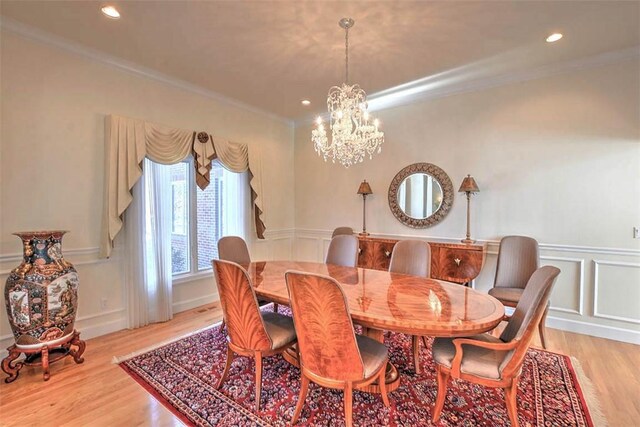 dining room featuring ornamental molding, recessed lighting, light wood-style flooring, an inviting chandelier, and a decorative wall