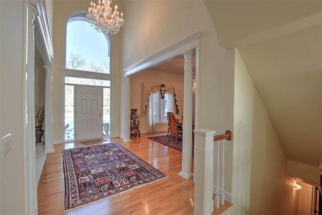 foyer with light wood-type flooring, an inviting chandelier, and a towering ceiling