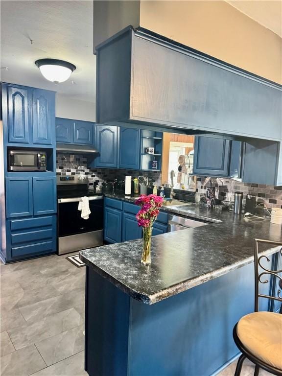 kitchen with a peninsula, open shelves, appliances with stainless steel finishes, blue cabinets, and decorative backsplash