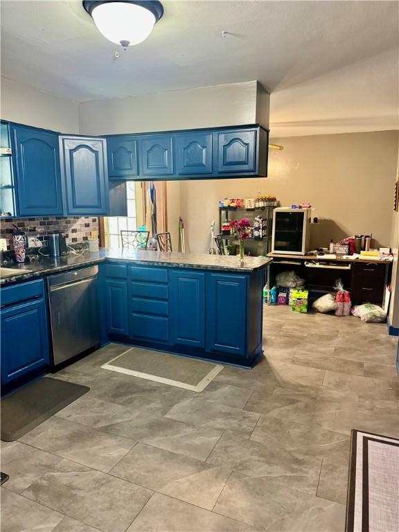 kitchen with a peninsula, dishwasher, blue cabinetry, and backsplash