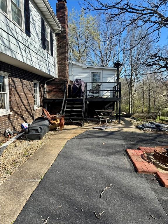 view of side of home featuring brick siding, a deck, and a chimney