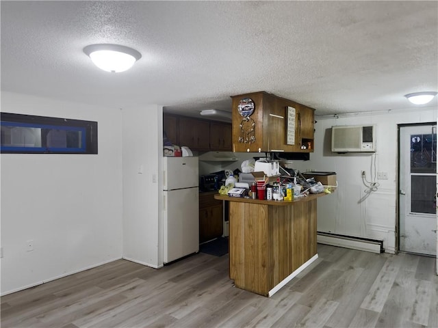 1511 E Fayette Ave, Teutopolis, IL 62467 - kitchen with freestanding refrigerator, a textured ceiling, light wood-style flooring, baseboard heating, and a wall unit AC