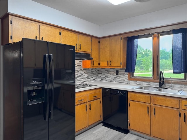 1511 E Fayette Ave, Teutopolis, IL 62467 - kitchen with black appliances, light wood-style flooring, under cabinet range hood, backsplash, and light countertops