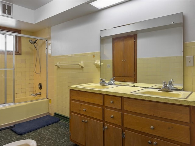 1511 E Fayette Ave, Teutopolis, IL 62467 - bathroom with tile walls, double vanity, bath / shower combo with glass door, and a wainscoted wall