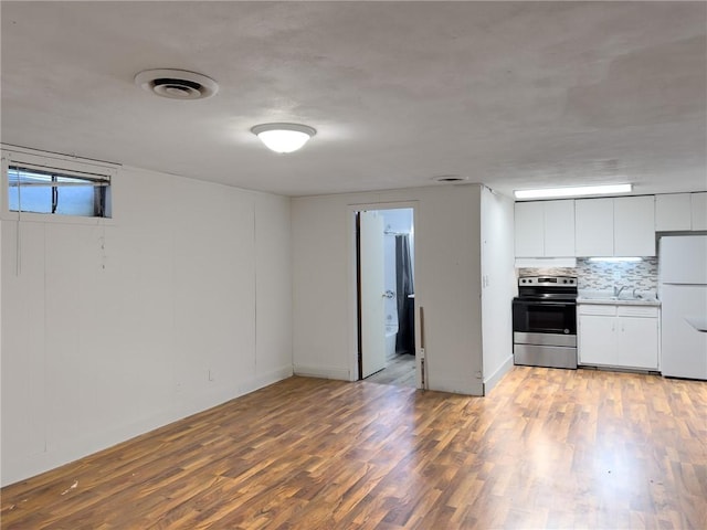 1511 E Fayette Ave, Teutopolis, IL 62467 - kitchen with stainless steel electric range, freestanding refrigerator, light wood-style floors, white cabinetry, and backsplash