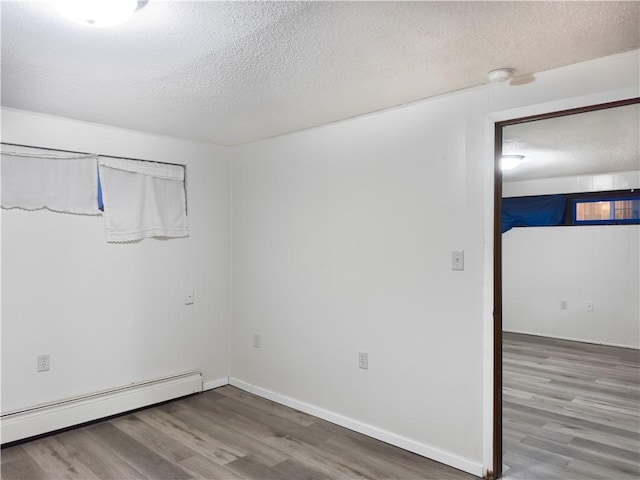 1511 E Fayette Ave, Teutopolis, IL 62467 - empty room with baseboard heating, a textured ceiling, and wood finished floors