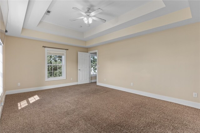 unfurnished room featuring carpet, a tray ceiling, and ceiling fan