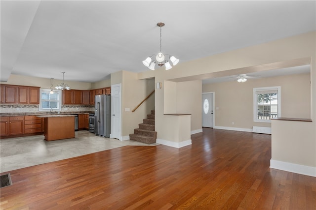 kitchen with ceiling fan with notable chandelier, light hardwood / wood-style floors, hanging light fixtures, and high quality fridge