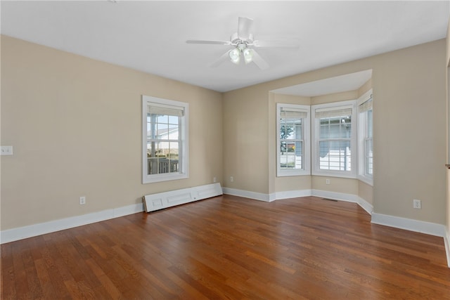 spare room with a healthy amount of sunlight, dark hardwood / wood-style floors, and a baseboard heating unit