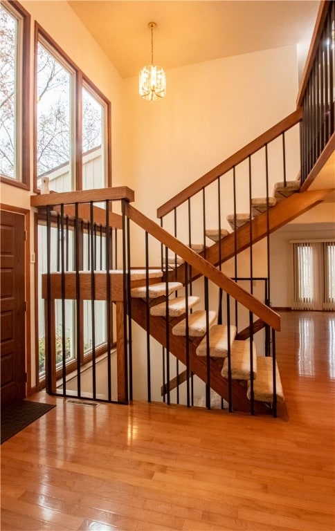 stairway featuring wood-type flooring and an inviting chandelier