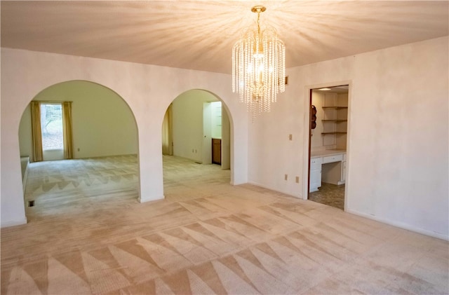 empty room featuring light carpet and a chandelier