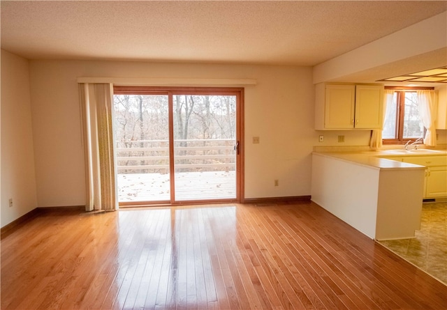 unfurnished living room with light hardwood / wood-style flooring, a textured ceiling, and sink