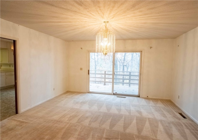 carpeted spare room with a textured ceiling and a chandelier