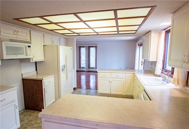 kitchen with white cabinetry, white appliances, kitchen peninsula, and sink