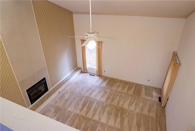 unfurnished living room with ceiling fan, carpet floors, ornamental molding, and high vaulted ceiling