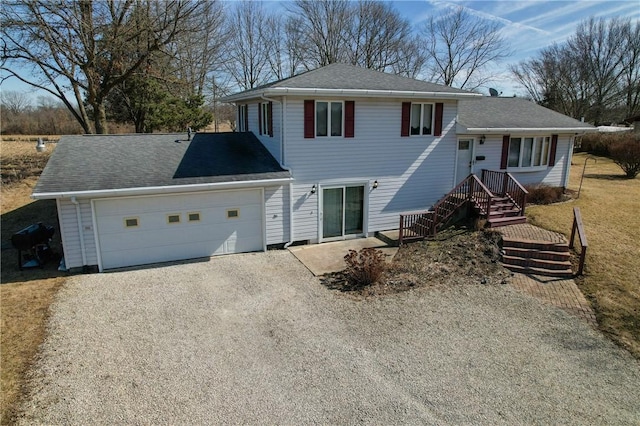 tri-level home with a garage, driveway, and roof with shingles