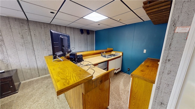 office space featuring a paneled ceiling, wood walls, and carpet