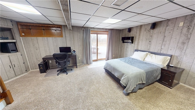 carpeted bedroom featuring access to outside, a drop ceiling, and wood walls