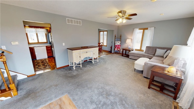 carpeted living room featuring ceiling fan, stairs, visible vents, and baseboards