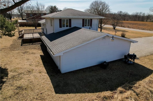 view of side of home featuring a shingled roof and a deck