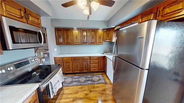 kitchen featuring ceiling fan, light wood-style floors, light countertops, appliances with stainless steel finishes, and brown cabinetry