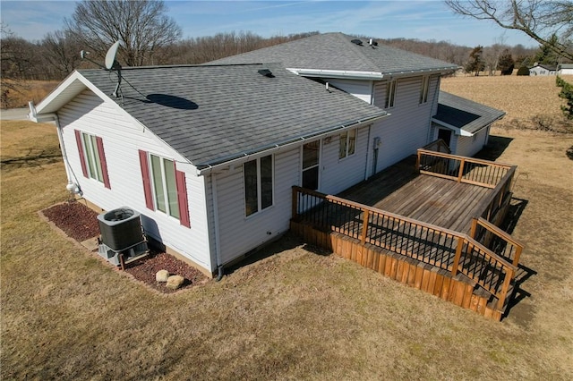 rear view of property featuring central AC, a shingled roof, a lawn, and a wooden deck