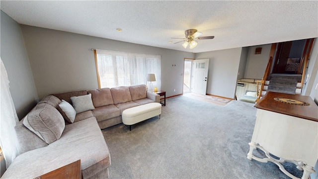 carpeted living room with ceiling fan, stairs, baseboards, and a textured ceiling