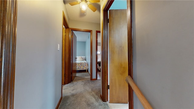 hall with carpet floors, a textured ceiling, and baseboards