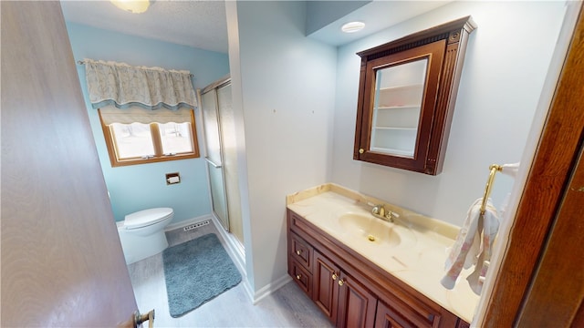 full bath featuring toilet, a stall shower, baseboards, and vanity