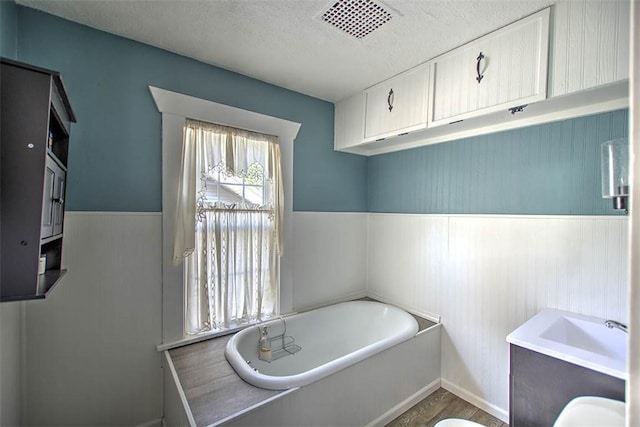 1470 W Decatur St, Decatur, IL 62522 - full bath with a bath, a wainscoted wall, a textured ceiling, and wood finished floors