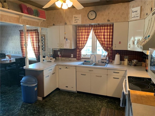 kitchen with white cabinets, white dishwasher, light countertops, and a sink