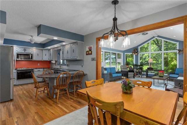 dining space with light wood-style floors, lofted ceiling, and a ceiling fan