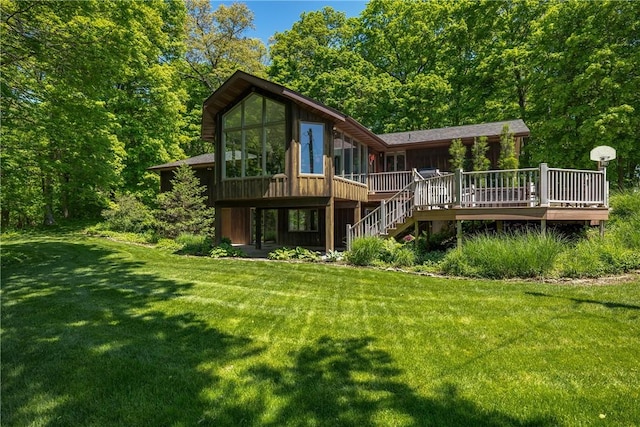 back of property with a wooden deck, stairway, a yard, and a sunroom