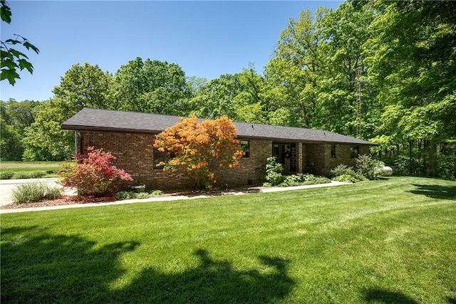 view of front facade with a front lawn, brick siding, and a view of trees