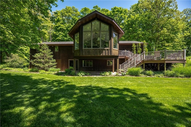 rear view of property with stairs, a deck, and a lawn