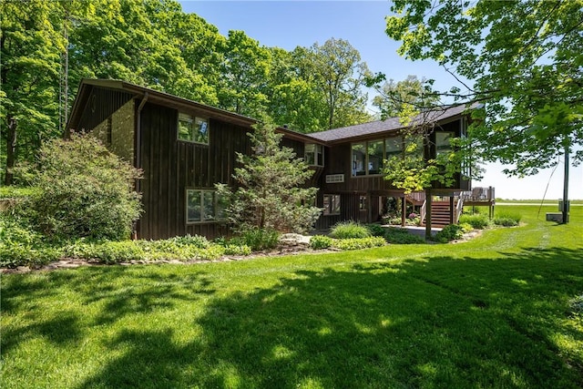 view of green lawn featuring stairs and a wooden deck